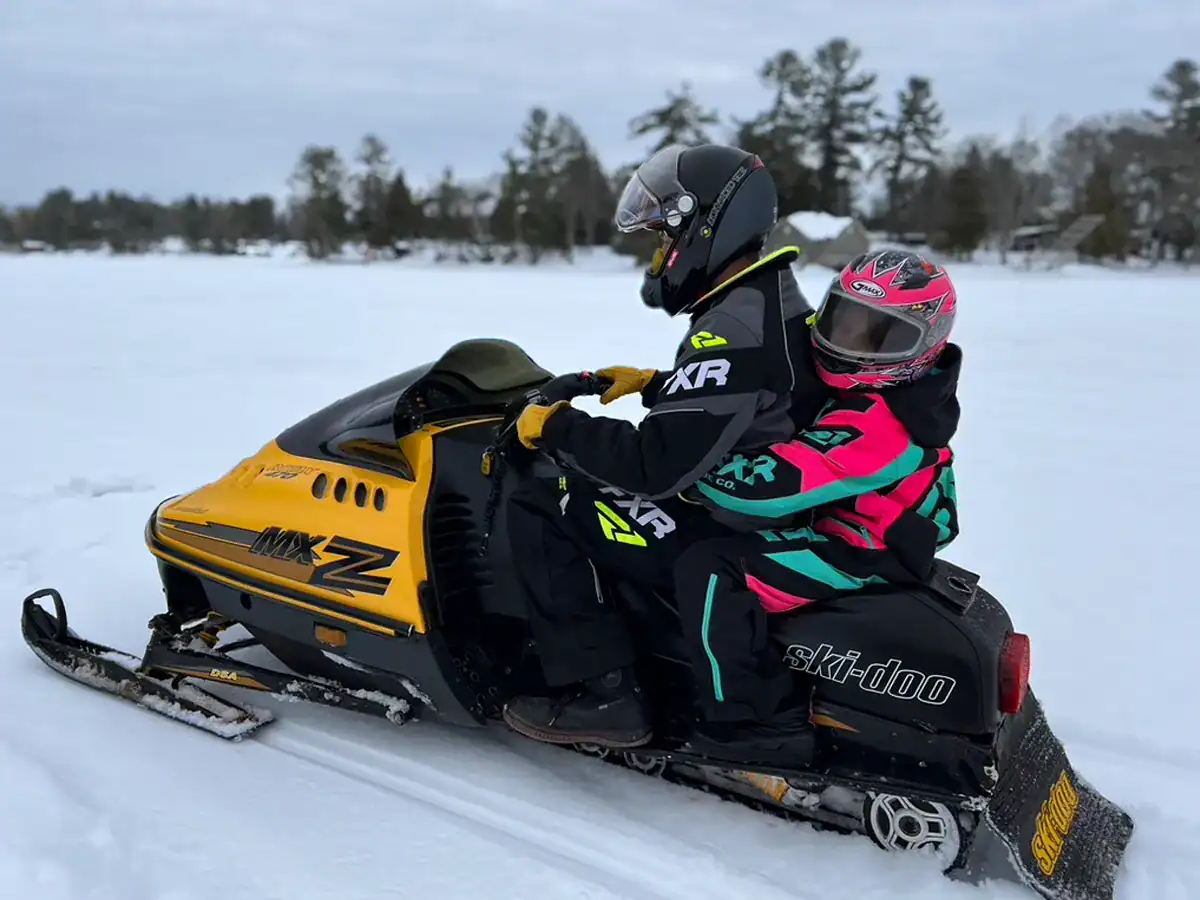 Father and daughter snowmobiling down the lake on a vintage 1992 Ski-Doo MXZ snowmobile 