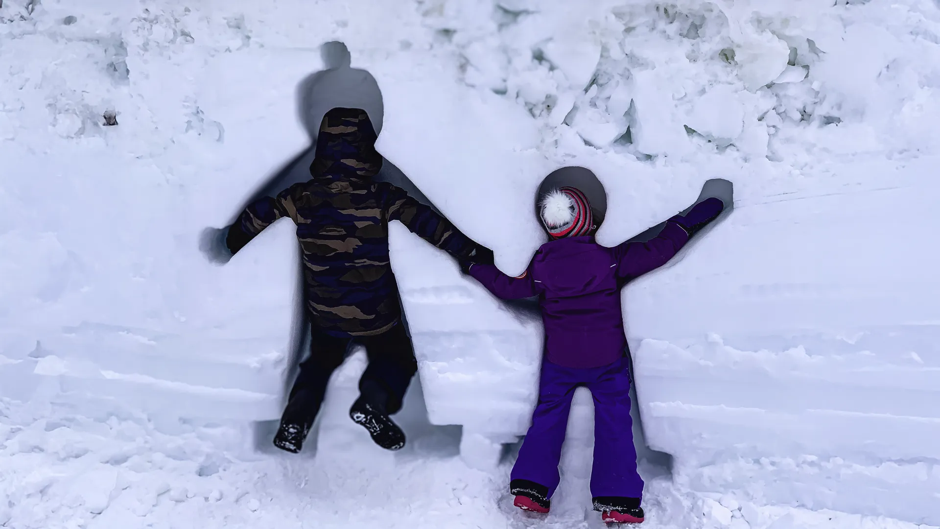 Two children have sculpted themselves in the snow at a family day winter festival