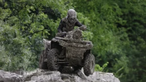 Mud-covered ATV rider at the summit of a steep, rocky incline, showcasing determination and skill in off-road riding.