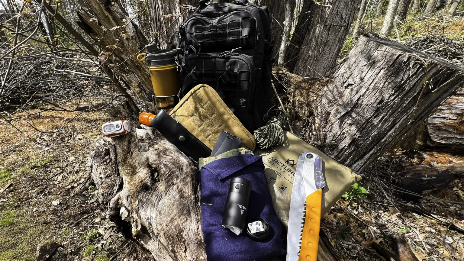 outdoor survival kit contents laid out on a log