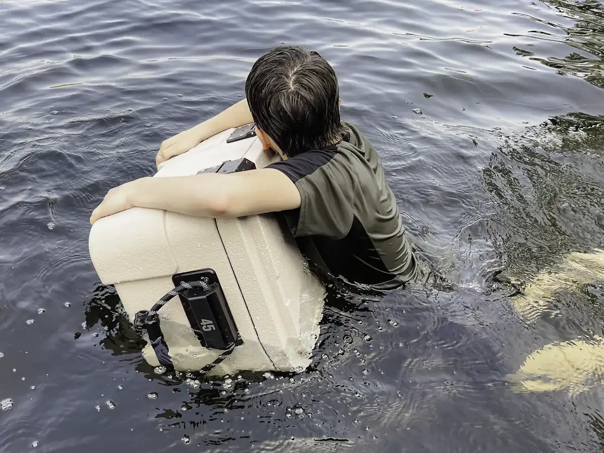 young man using the Rugged Road 45 cooler as a float