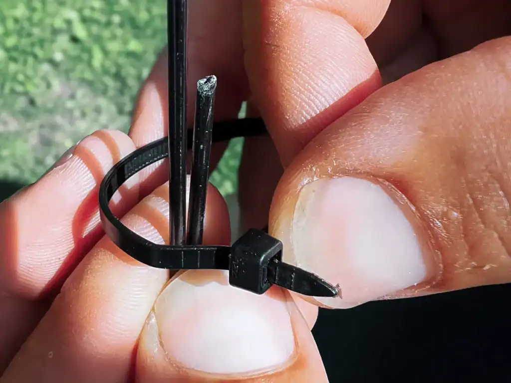 angler repairs a broken fishing rod with zip ties
