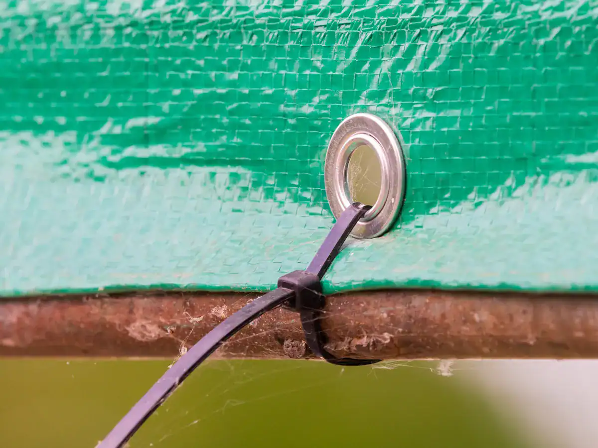 a tarp zip tied to a branch to create an emergency shelter