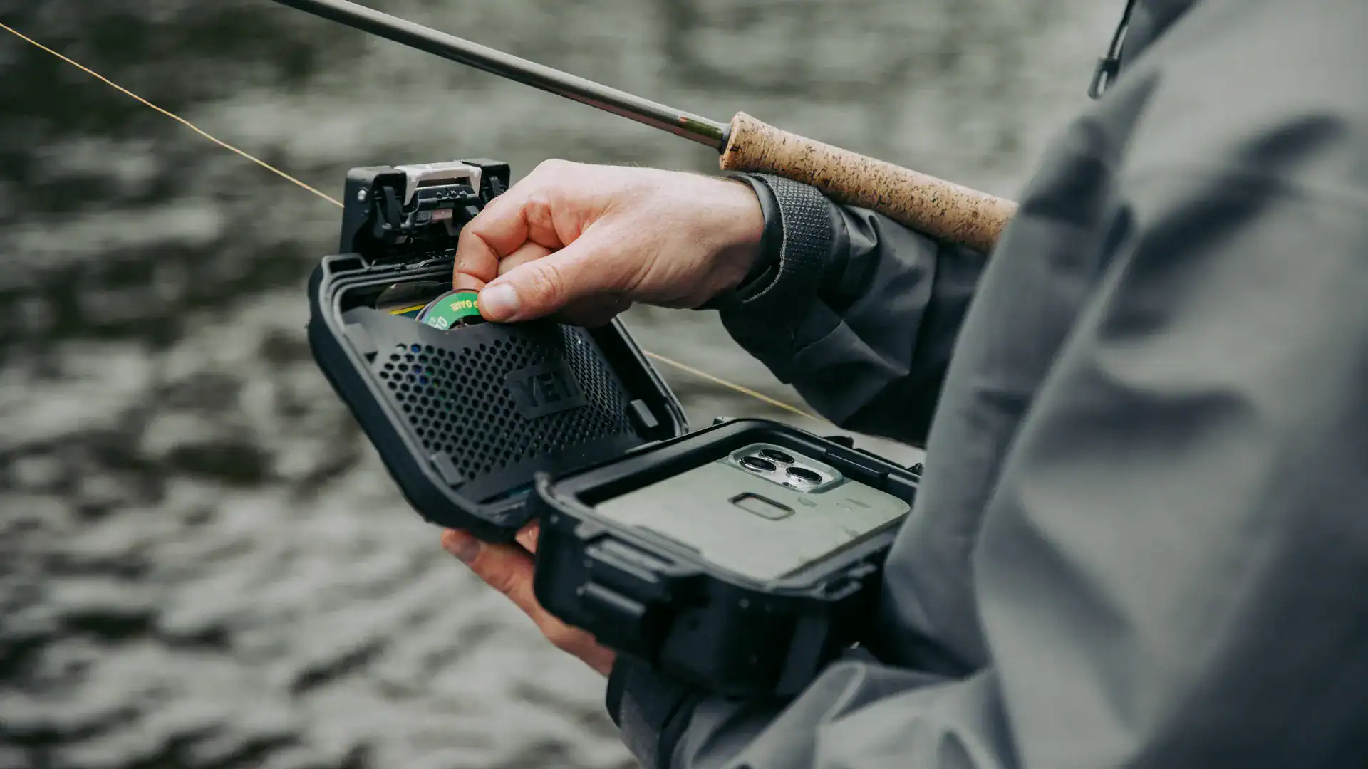 an angler holding a YETI LoadOut GoBox 1 waterproof gear case