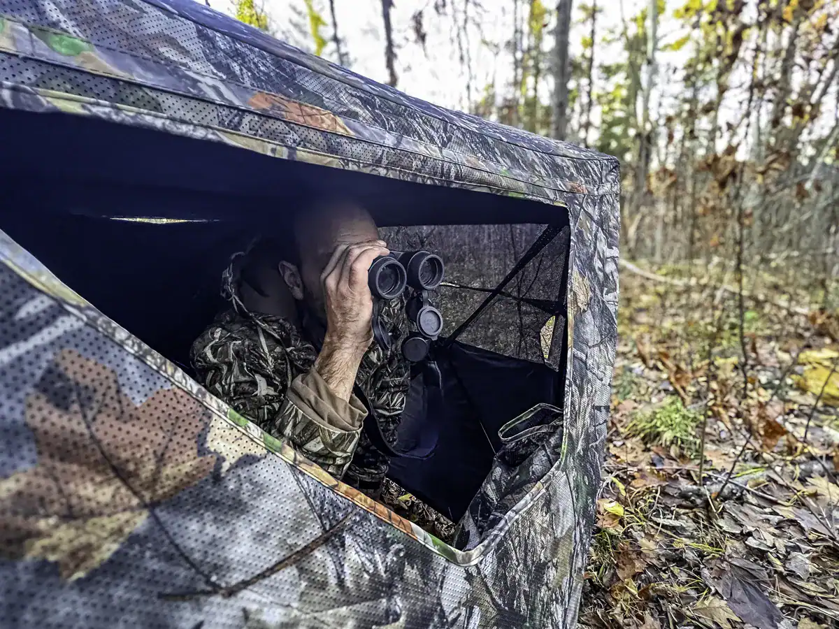 inside the ground blind a hunter is scouting for deer 