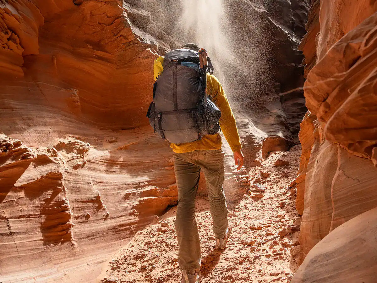 Hiker carrying the 60L men's YETI Skala in classic navy through the canyon