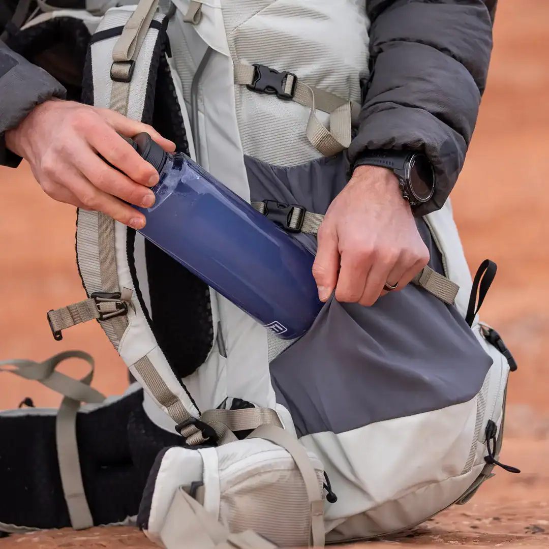Hiker removing a YETI plastic water bottle from the Skala hydration pocket