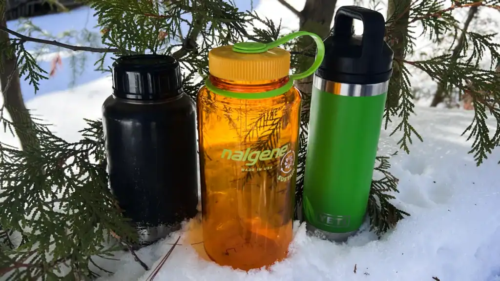 stainless steel water bottle, plastic Nalgene water bottle and a yeti double-insulated water bottle sitting in the snow