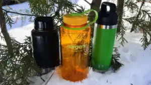 stainless steel water bottle, plastic Nalgene water bottle and a yeti double-insulated water bottle sitting in the snow