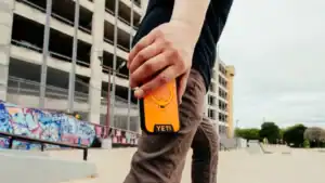 YETI’s NEW LoadOut Phone Case: Military-grade Protection for Your iPhone 4 skater holding the yeti loadout phone case in king crab orange