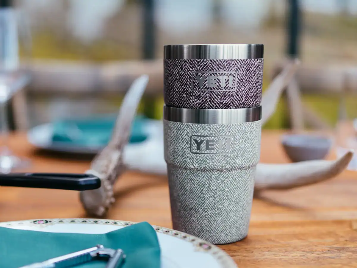 YETI's New Riverhead Collection: A Tweed-Textured Twist for Fall 1 on a picnic table YETI's Rambler Stackable Cups in the new red and green Riverhead collection colour way